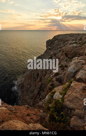 Tramonto dalle scogliere di Cap de Barbaria cape con mare mediterraneo, Sunray e nuvole in Formentera (Isole Baleari, Spagna) Foto Stock