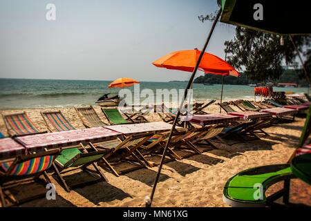 Lettini e ombrelloni sulla ochheuteal spiaggia turistica nelle vicinanze del porto e della città di Sihanoukville. Cambogia Foto Stock