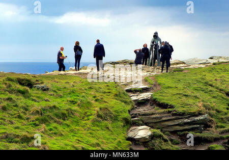 Tintagel, Cornwall, Regno Unito - 10 Aprile 2018: Turisti in posa per le fotografie al King Arthur statua Gallos da Rubin Eynon. Foto Stock