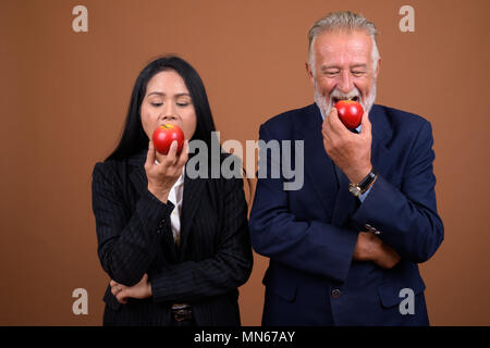 Coppia multi-etnico azienda giovane contro sfondo marrone Foto Stock