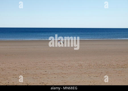 Due persone in sedie a sdraio su di una vasta apertura spiaggia vuota a Puerto Madryn, Chubut Provincia, Argentina. Foto Stock