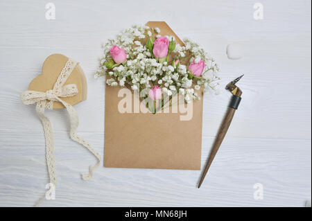 Calligrafica giù una busta con fiori rosa e una lettera Foto Stock