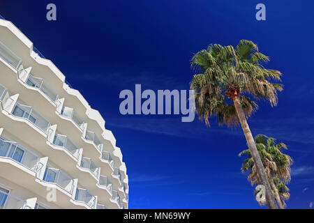 Hotel facciata contro il profondo blu del cielo, con palme Foto Stock