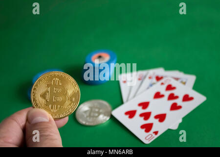 Due bitcoins recante sul verde tavolo del poker e il mazzetto di chip con carte in background|Oro|argento|blue|a filo Foto Stock