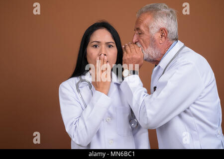 Coppia multi-etnico giovane medici contro lo sfondo marrone Foto Stock