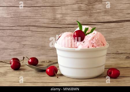 Ciotola di ciliegia di gelato al cioccolato, ancora vita su un sfondo di legno Foto Stock