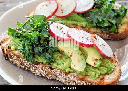 Una sana avocado toast close up con cavoli rapa e ravanelli su tutto il pane di grano Foto Stock