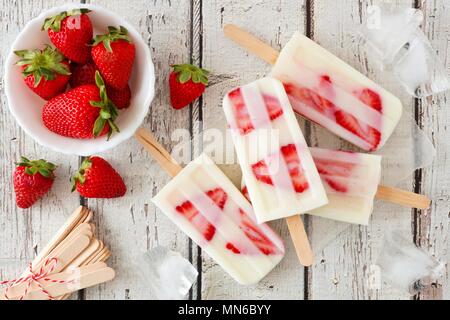 Gruppo di fragole fatta in casa vaniglia popsicles su un rustico di legno bianco sullo sfondo Foto Stock