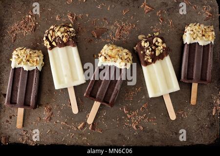 Cioccolato e mandorle bianche luci anabbaglianti e popsicles scuro, rustico sfondo metallico Foto Stock