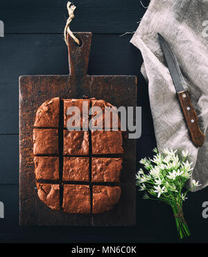 Cotto al forno rettangolare brownie al cioccolato torta è tagliato in quadrati, un legno nero tabella Foto Stock