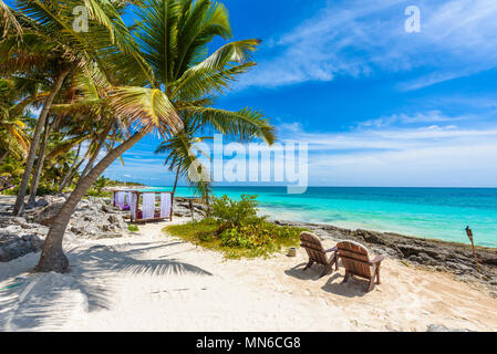 Sedie e amaca sotto le palme sulla spiaggia paradiso al resort tropicale. Riviera Maya - Caraibi costa a Tulum in Quintana Roo, Messico Foto Stock