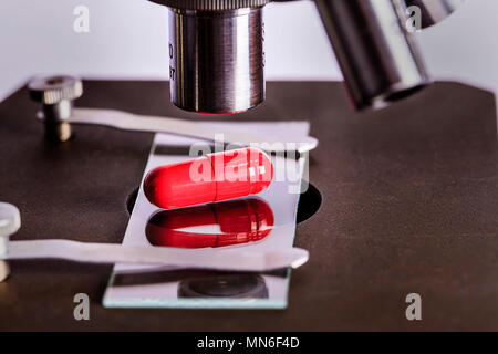 Laboratorio di Scienze sicuro di ricerca di nuovi farmaci, microscopio e pillole di rosso Foto Stock