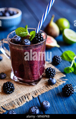 Un sano frullato di blackberry con fichi, mirtillo e calce in un vasetto di vetro Foto Stock