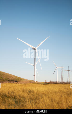 Le turbine eoliche con la linea di alimentazione al tramonto Foto Stock