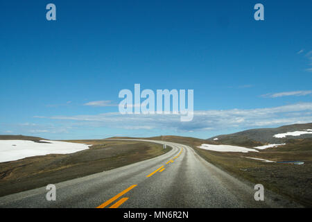 Sulla strada per il Capo Nord in Norvegia. Una vista panoramica della strada e il paesaggio arido nella Norvegia del nord. L'ultima neve dell'inverno è di fusione Foto Stock