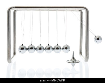 Fisica al lavoro con un Newton culla oscillante ed una sommità di filatura su un sfondo isolato Foto Stock