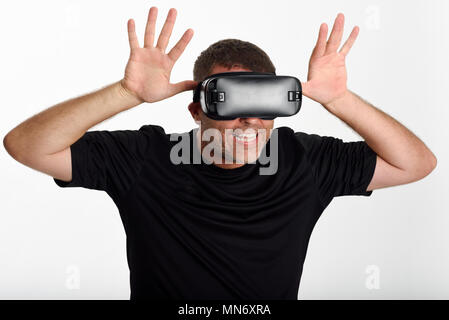 Uomo che guarda in VR bicchieri e gesti con le mani. Bella sorpresa ragazzo indossa la realtà virtuale occhiali per guardare film o giocare con i videogiochi, isolato su sfondo bianco. Foto Stock