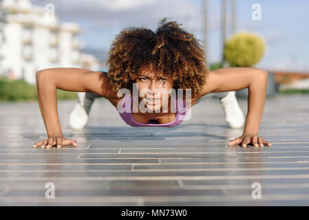 Montare Nero donna fa pushups sul piano urbano. Giovane donna che lavora fuori in strada. Foto Stock