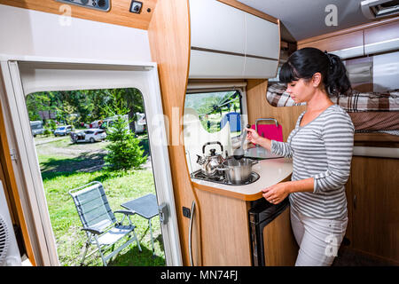 Donna cucinare in camper, camper interni. Vacanza per la famiglia in viaggio, viaggio vacanza in camper, caravan auto vacanza. Foto Stock