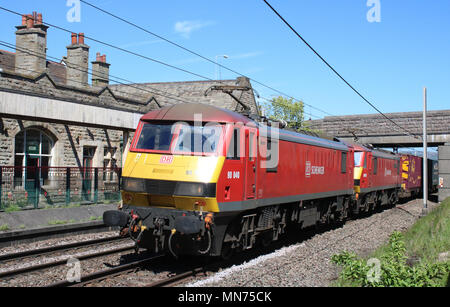 Classe 90 i treni elettrici in rosso DB Schenker livrea trasporta un contenitore treno lungo la linea principale della costa occidentale passando per Carnforth. Foto Stock