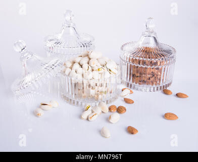 Mandorle e pistacchi in recipiente di vetro su uno sfondo Foto Stock