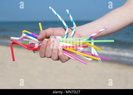 Stretta di mano azienda cannucce di plastica spiaggia di inquinanti Foto Stock