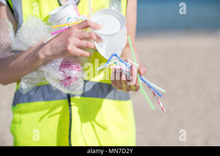Close Up di persona la raccolta dei rifiuti di plastica da spiaggia inquinati Foto Stock