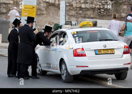 Gli ebrei ortodossi ordinare un taxi sulla strada di Gerusalemme Foto Stock