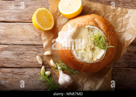 La Fonduta di un filone di pane da fusi formaggio camembert close-up su una tavola orizzontale di vista in pianta da sopra Foto Stock