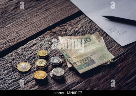 Lucidare il denaro sul tavolo, le banconote e le monete metalliche. Pezzo di carta e matita. Foto Stock