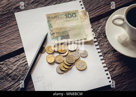 Lucidare il denaro sul tavolo, le banconote e le monete metalliche. Pezzo di carta e matita. Il caffè. Foto Stock