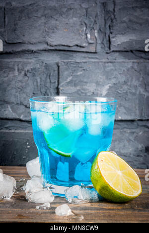 Estate colorata bevanda ghiacciata laguna blu alcool bere cocktail con lime e menta, corteccia sfondo spazio di copia Foto Stock