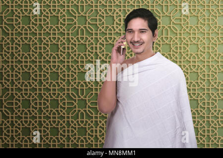 Bello asian uomo pellegrino parlando al telefono cellulare con esclusivo disegno sullo sfondo della parete Foto Stock