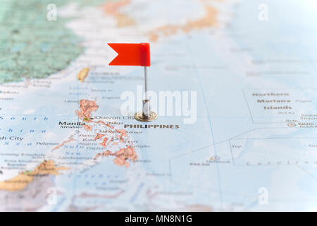 Piccola bandiera rossa la marcatura delle Filippine su una mappa del mondo. Foto Stock