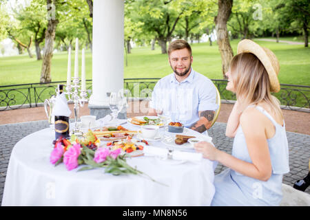 Giovane coppia adorabile avente colazione romantica seduti all'aperto nel bellissimo giardino di Apple Foto Stock