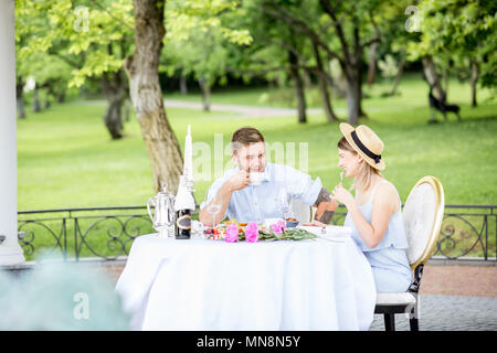 Giovane coppia adorabile avente colazione romantica seduti all'aperto nel bellissimo giardino di Apple Foto Stock