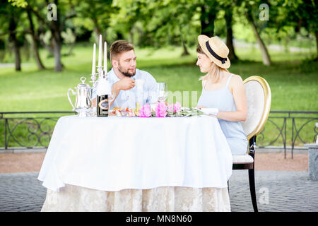 Giovane coppia adorabile avente colazione romantica seduti all'aperto nel bellissimo giardino di Apple Foto Stock