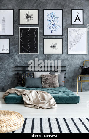 Il beige un lenzuolo sul materasso verde in camera da letto moderna con interni galleria sul muro di cemento Foto Stock
