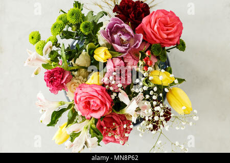 Vista dall'alto di coloratissimi bouquet di fiori di primavera - Rosa Rose e Tulipani gialli, su sfondo grigio Foto Stock