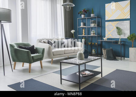 Poltrona verde accanto a un beige divano nel soggiorno interno con dipinti  di oro e piante Foto stock - Alamy