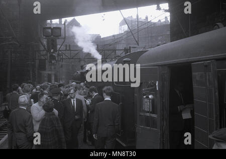 Anni sessanta, foto storiche che mostra un gruppo di persone in attesa da una locomotiva a vapore al di fuori su una piattaforma a Liverpool la stazione ferroviaria di Lime Street, England Regno Unito. Foto Stock