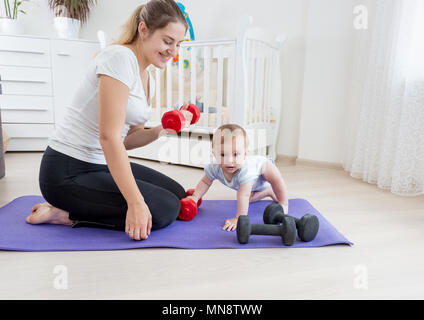 Giovane e bella madre che fa fitness in casa con il suo bambino Foto Stock