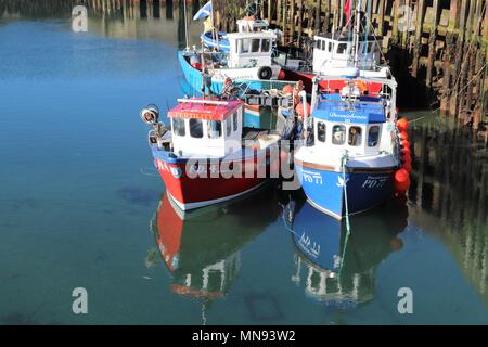 Cinque, piccole e colorate barche da pesca per la pesca dell'aragosta in porto con riflessi in acqua Foto Stock