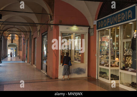 Bologna. Donna anziana guarda nella vetrina di un negozio, portici di Strada Maggiore. L'Italia. Foto Stock