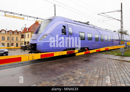 Tomelilla, Svezia - 15 Aprile 2017: uno blu classe X61 commuter train passando un passaggio a livello nella città Tomelilla. Foto Stock