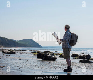 Charmouth, Dorset, Regno Unito. Il 15 maggio 2017. Regno Unito: Meteo A walker gode di sole e cielo blu come si consulta una mappa su di una spiaggia deserta vicino a Charmouth questa mattina. I visitatori sono attesi per il gregge alla Jurassic Coast durante il fine settimana quando le temperature sono impostati a salire ancora una volta. Credito: Celia McMahon/Alamy Live News. Foto Stock