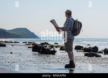 Charmouth, Dorset, Regno Unito. Il 15 maggio 2017. Regno Unito: Meteo A walker gode di sole e cielo blu come si consulta una mappa su di una spiaggia deserta vicino a Charmouth questa mattina. I visitatori sono attesi per il gregge alla Jurassic Coast durante il fine settimana quando le temperature sono impostati a salire ancora una volta. Credito: Celia McMahon/Alamy Live News. Foto Stock