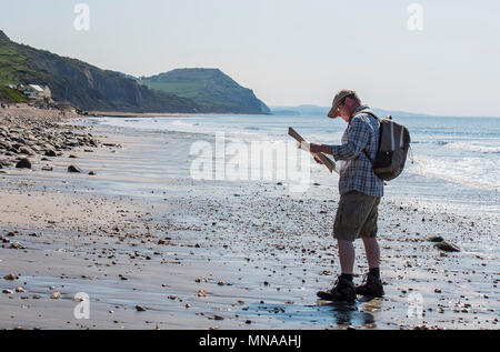 Charmouth, Dorset, Regno Unito. Il 15 maggio 2017. Regno Unito: Meteo A walker gode di sole e cielo blu come si consulta una mappa su di una spiaggia deserta vicino a Charmouth questa mattina. I visitatori sono attesi per il gregge alla Jurassic Coast durante il fine settimana quando le temperature sono impostati a salire ancora una volta. Credito: Celia McMahon/Alamy Live News. Foto Stock