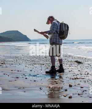 Charmouth, Dorset, Regno Unito. Il 15 maggio 2017. Regno Unito: Meteo A walker gode di sole e cielo blu come si consulta una mappa su di una spiaggia deserta vicino a Charmouth questa mattina. I visitatori sono attesi per il gregge alla Jurassic Coast durante il fine settimana quando le temperature sono impostati a salire ancora una volta. Credito: Celia McMahon/Alamy Live News. Foto Stock