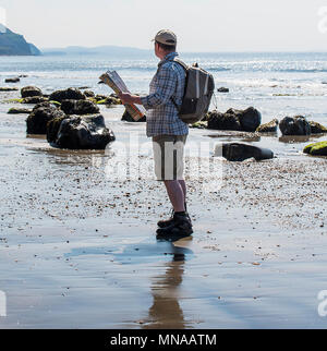 Charmouth, Dorset, Regno Unito. Il 15 maggio 2017. Regno Unito: Meteo A walker gode di sole e cielo blu come si consulta una mappa su di una spiaggia deserta vicino a Charmouth questa mattina. I visitatori sono attesi per il gregge alla Jurassic Coast durante il fine settimana quando le temperature sono impostati a salire ancora una volta. Credito: Celia McMahon/Alamy Live News. Foto Stock